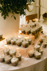 Desserts in small jars displayed elegantly at a wedding reception during evening hours in a luxurious venue