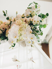 Floral arrangement featuring white orchids and roses at a wedding venue in a bright, elegant setting