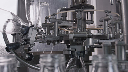 Modern bottling machine filling glass bottles in
