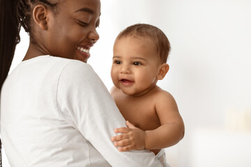 Children Happiness. Portrait of adorable African American baby smiling, young afro mum holding and hugging her little child, playing together, white background, free copy space, banner