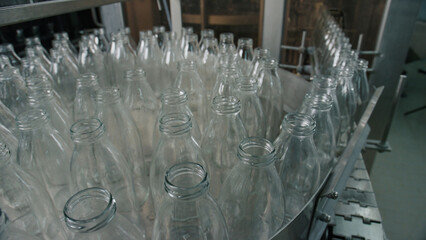 Empty glass bottles moving on conveyor belt in