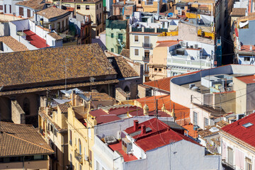 Aerial view of densely packed rooftops in Valencia, showcasing a mix of traditional tile designs...