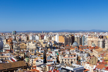 Panoramic view of Valencia city rooftops under a clear blue sky, showcasing diverse architecture and vibrant urban life, ideal for travel and cityscape themes.