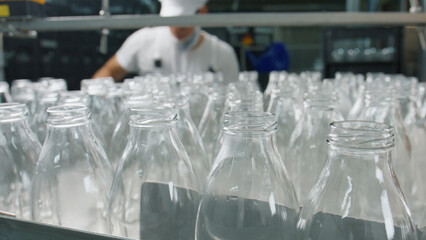 Many empty glass bottles passing on conveyor belt