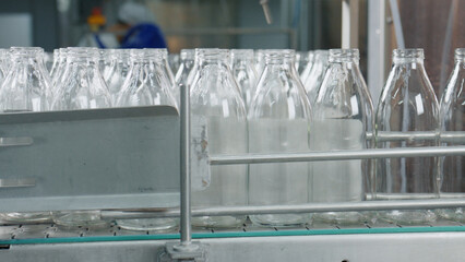 Empty glass bottles moving on conveyor belt in