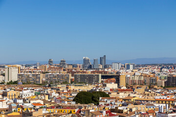 A panoramic view of Valencia, showcasing a mix of modern skyscrapers and traditional architecture under a clear blue sky. Urban living and vibrant city life captured.