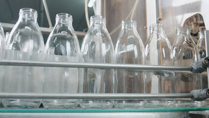 Empty glass bottles moving on industrial conveyor