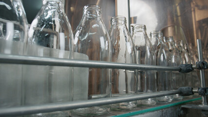 Empty glass bottles moving on conveyor belt in