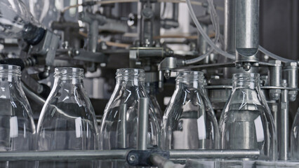 Empty glass bottles moving along conveyor belt in