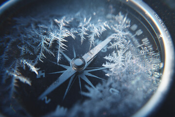 A close-up of abstract frost crystals forming intricate patterns on the glass face of a cold, metallic compass.