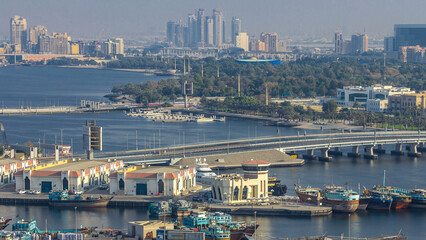 Fototapeta premium Dubai creek landscape timelapse with boats and ship in port and modern buildings in the background during sunset