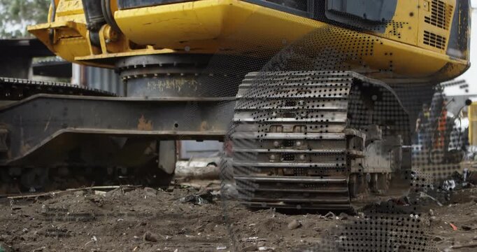 Yellow excavator track engaging on muddy site, rotating and leveling soil for groundwork