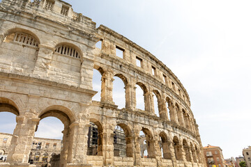 Ancient amphitheater showcasing impressive stone architecture, arches, and historical significance, surrounded by modern urban landscape and clear sky