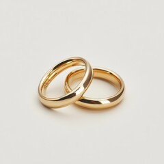 Two shiny gold wedding rings intertwined on a clean white background isolated on white background