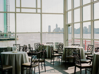 Bright waterfront venue with elegant tables and city skyline view during midday