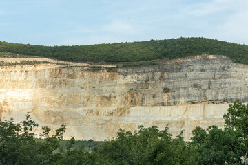 Quarry landscape showcasing mineral extraction with layered rock formations and lush greenery, highlighting the mining process and natural environment