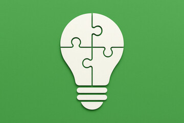White Puzzle Lightbulb on Green Background – Innovation and Problem-Solving Concept