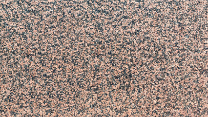 Textured surface of pink granite stone with intricate patterns and speckles, showcasing natural beauty and geological features, ideal for backgrounds and design projects