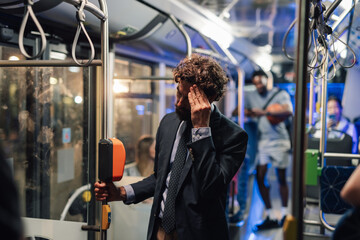 Stressed businessman touching head on bus at night