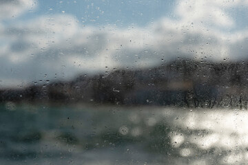 A blurry abstract view of sea, land and sky seen through a misty, wet glass