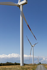 A striking close-up view of several wind turbines extending into the sky, showcasing their...