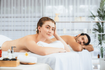Blissful couple customer having exfoliation treatment in luxury spa salon with warmth candle light...