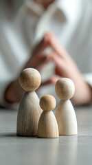 Wooden peg figures representing family members with blurred background of clasped hands people child