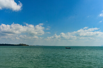 Thai traditional long-tail boat rests on calm turquoise waters of Andaman sea under a cloudy sky.