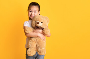 My Favorite Toy. Portrait of adorable little preschool asian girl holding teddy bear in hands,...