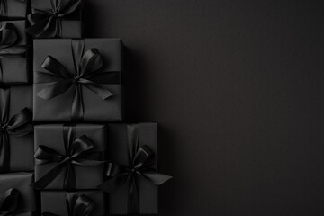 Luxurious black gift boxes with tied ribbons displayed on a solid dark backdrop enhancing the...