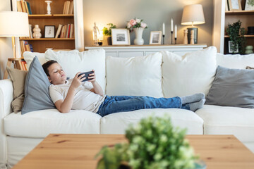 Couch, boy with phone for games, movies or streaming cartoon weekend in home. Entertainment, relax or kid gaming on sofa with mobile connection for video, playing online or addiction.