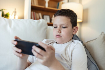 Cute boy, streaming and smartphone for educational games, growth and development in home. Kids, mobile tech and esports for creativity, fun and social media with application, download and playing.