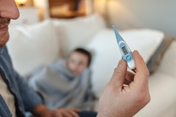 Cropped shot of a man checking his son's temperature.
