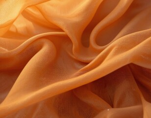 Close up of flowing sheer orange fabric with soft folds and texture