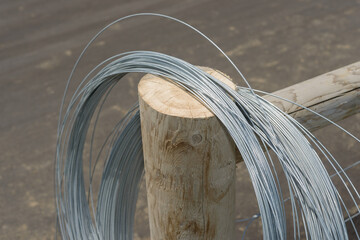 spool of high-tensile metal wire, typically used for outdoor perimeter fencing on wooden posts