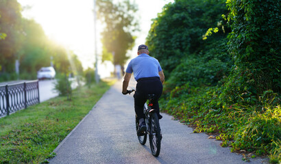 Fototapeta premium Senior man cycling along a scenic path during sunset in a quiet urban area