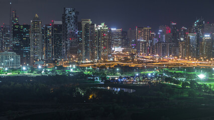 Fototapeta premium Jumeirah lake towers and Dubai marina skyscrapers and golf course night timelapse, Dubai, United Arab Emirates