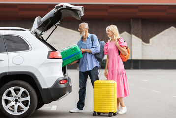 Happy caucasian senior couple going car trip together. Cheerful elderly man and woman in casual...
