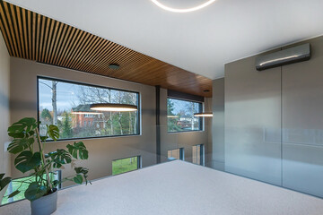 Stylish interior design of a country house in high-tech style. Large windows with a beautiful view of trees and a green lawn.