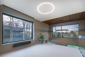 Modern architectural interior design of a country house in high-tech style. Laconic 
decoration of the room. Large windows with a beautiful view.