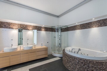 Exclusive bathroom design. A modern shower cabin, a bathtub with hydro massage is decorated with brown mosaic tiles. Rotating mirrors on the countertop with sink bowls.