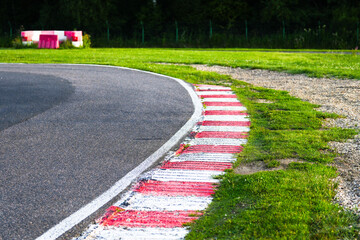 acing circuit featuring a red and white striped curb along a smooth asphalt track. The scene is...