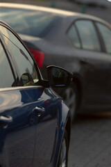 In a parking lot, there is a blue car that is parked right next to a black car, creating a striking contrast between the two vehicles