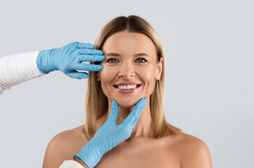 Portrait of smiling middle aged beautiful blonde woman getting prepared for plastic surgery...