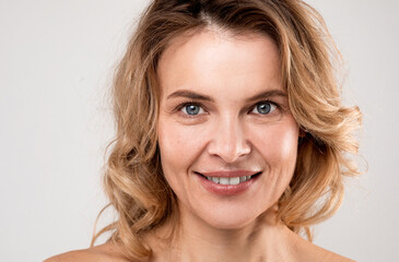 Closeup Portrait Of Smiling Attractive Middle Aged Woman With Bare Shoulders Posing Over Light...