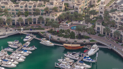 Aerial view on yachts floating in Dubai marina timelapse. White boats are in green canal water.