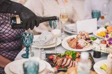 Elegant evening gathering featuring a lavish feast and sparkling wine in a beautifully set venue, showcasing fine dining and delightful company among friends