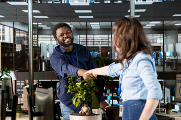Multiethnic business workers greeting their new colleague at the office, shaking hands when she...