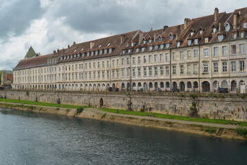 Historic French waterfront promenade showing 17th century arcaded buildings along River Doubs in Besançon for travel and architectural concepts