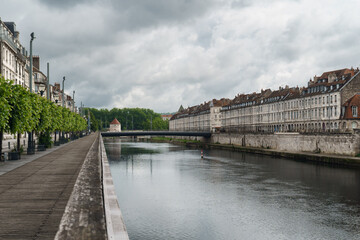 Historic French waterfront promenade showing 17th century arcaded buildings along River Doubs in Besançon for travel and architectural concepts
